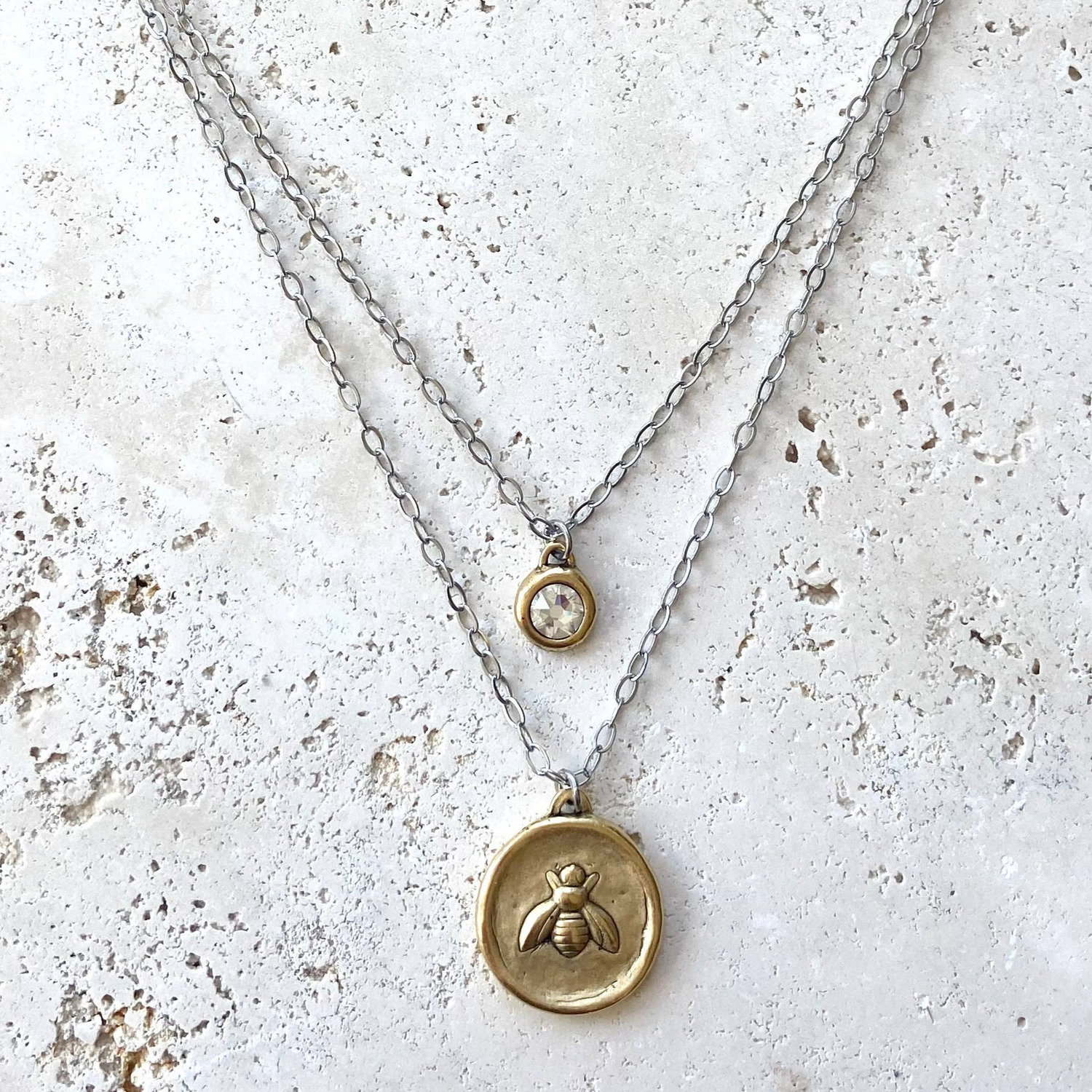 Two necklaces with pendants on a textured white surface