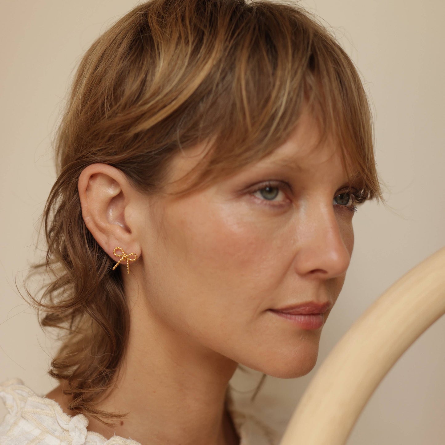 woman wearing a gold bow stud earring