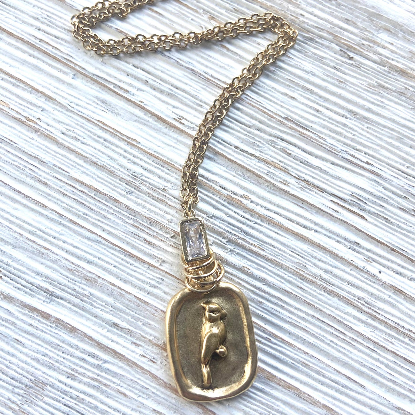 Gold necklace with a pendant featuring a dog design on a textured surface