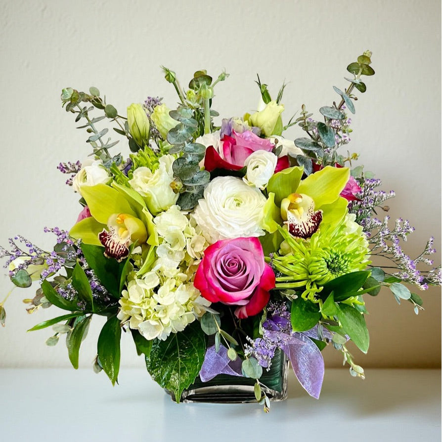 flower arrangement with purple, green and white roses, orchids, hydrangea