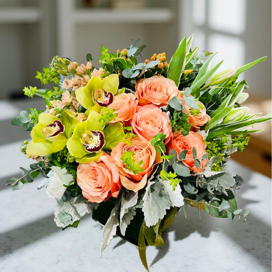 peach roses, green orchids, tulips, stock, berries in a low and lush flower arrangement