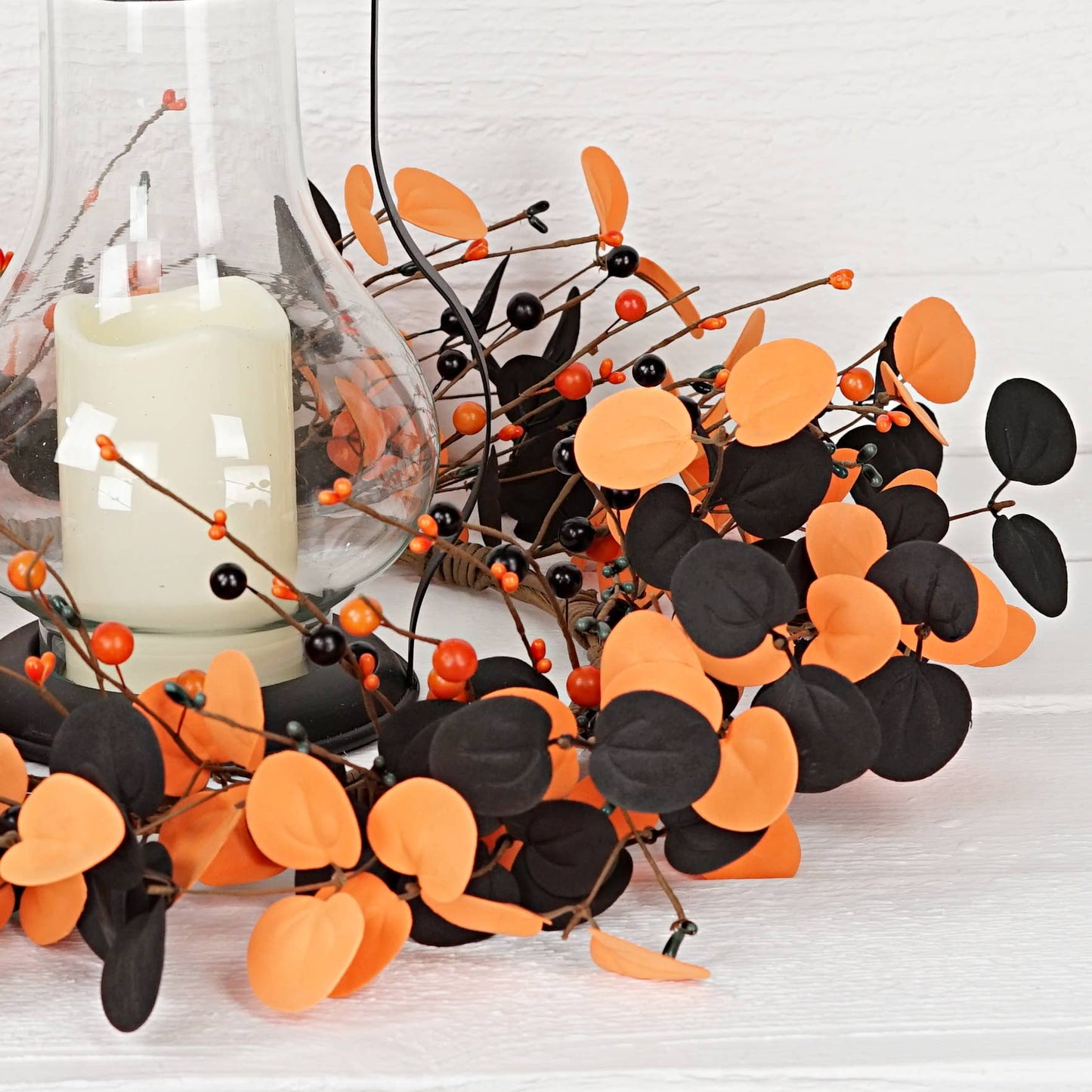 Decorative branches with orange and black leaves on a white surface.