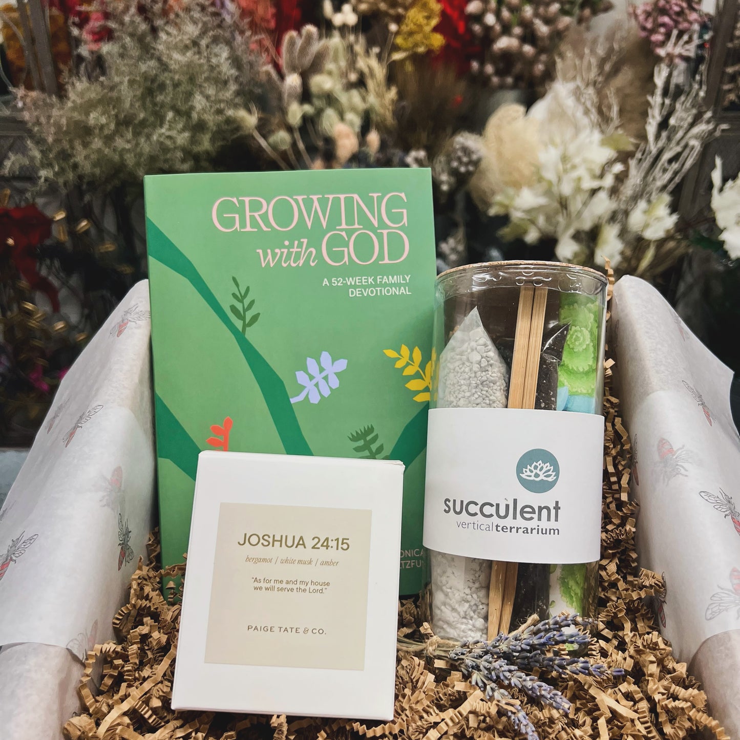 Gift set with 'Growing with God' devotional, succulent terrarium, and motivational candle on a floral background.