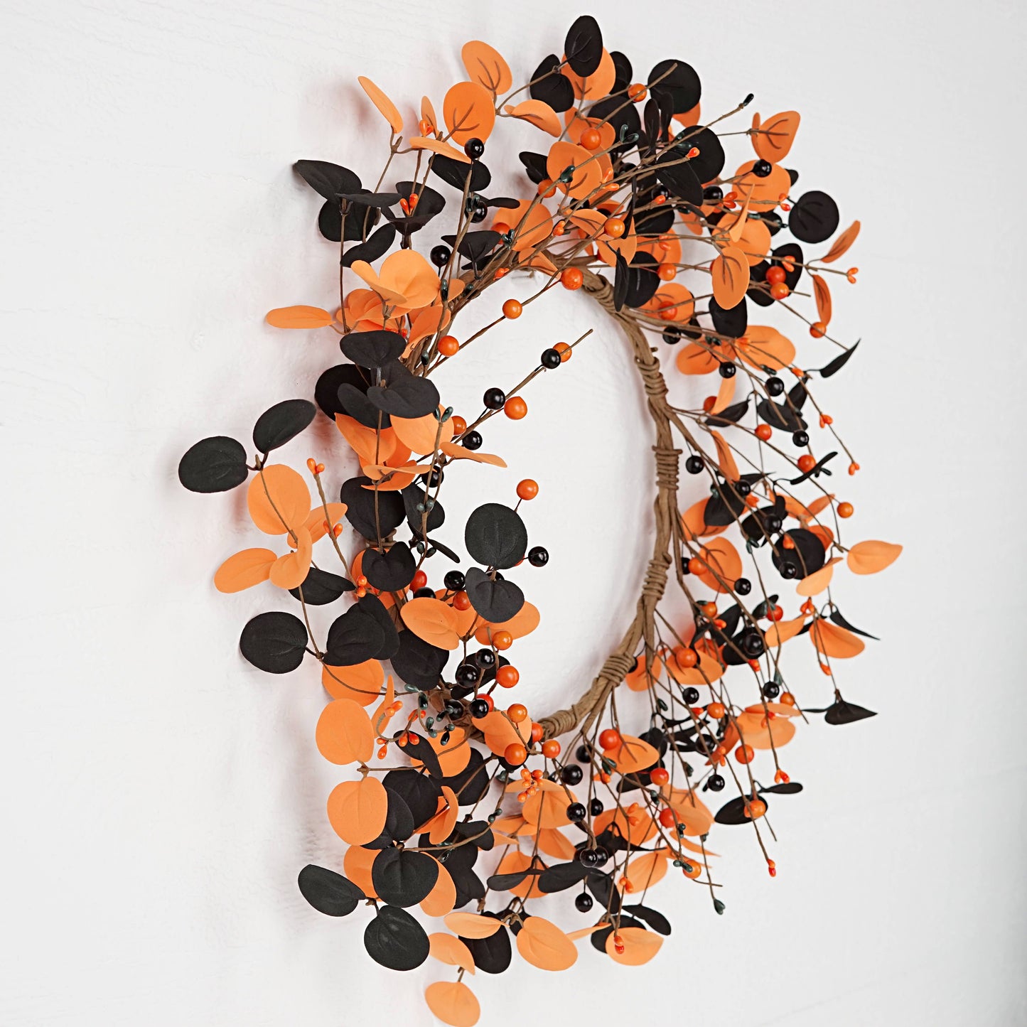 Decorative wreath with orange and black leaves on a white background