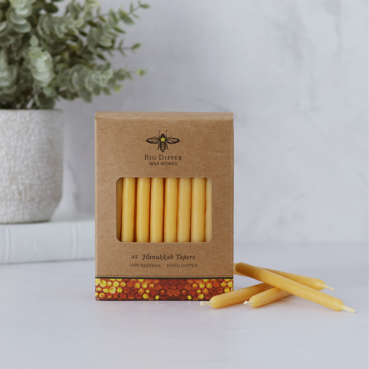 Box of Hanukkah candles with beeswax candles on a white surface