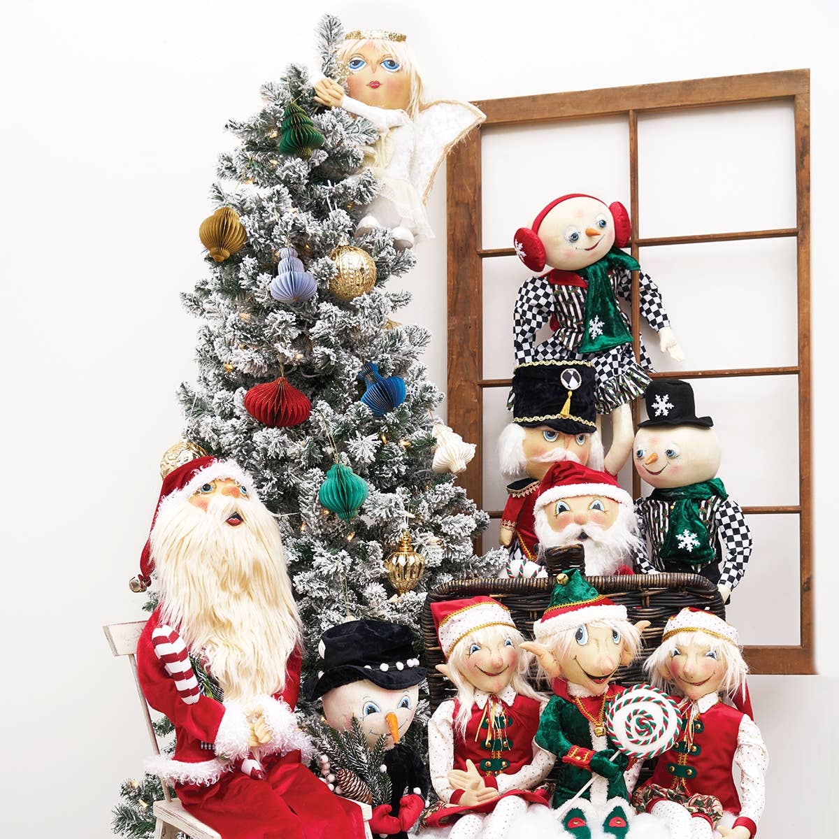 Decorative Christmas tree with ornaments and a group of festive dolls in front.
