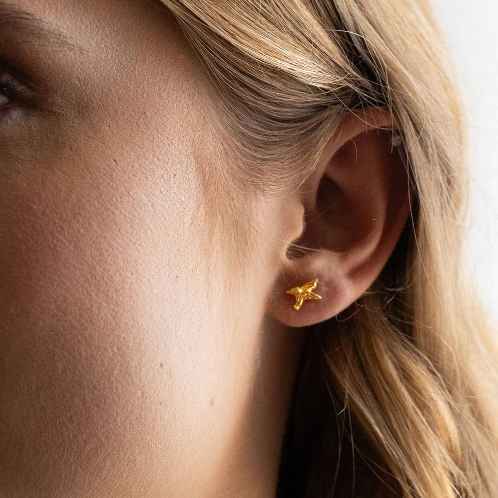 gold hummingbird earring on an ear