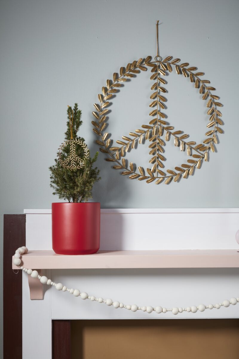 peace sign wreath hanging above a mantle with a small potted plant next to it
