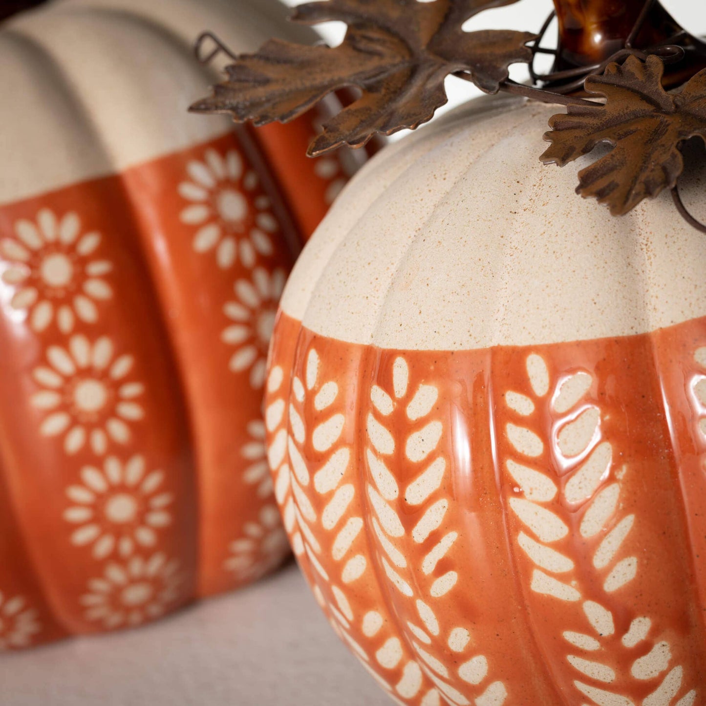Decorative ceramic pumpkins with white patterns on a neutral background