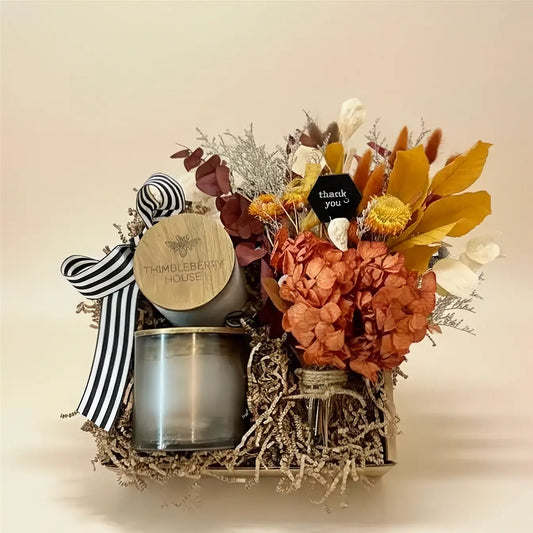 Gift basket with flowers, a candle, and decorative items on a beige background