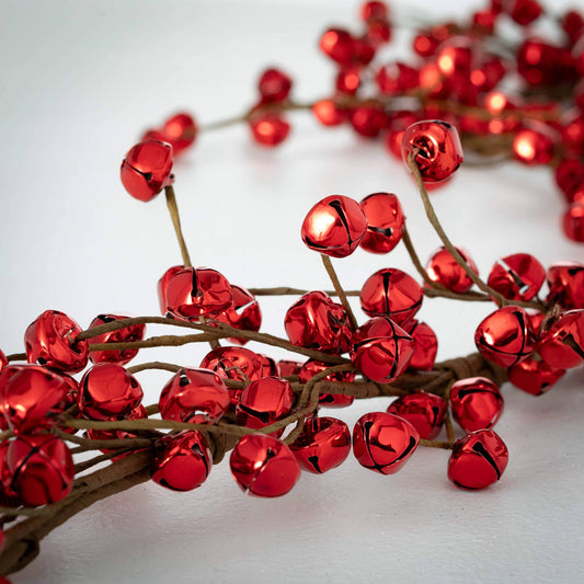 Red metallic jingle bells on a branch against a white background