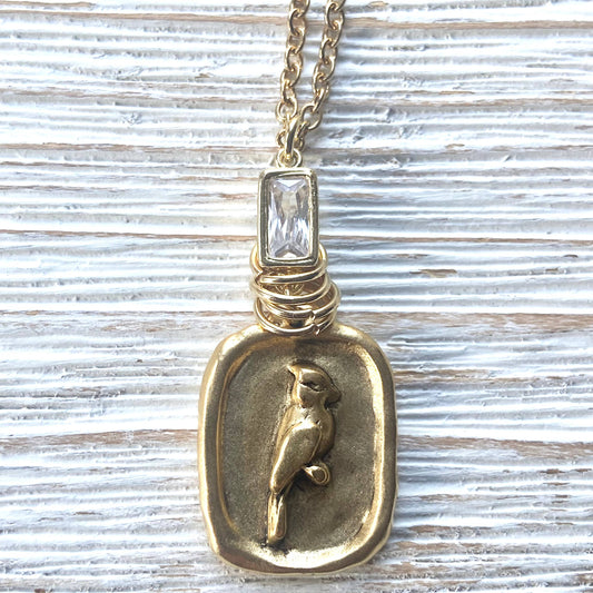 Gold pendant with cardinal design on a textured surface
