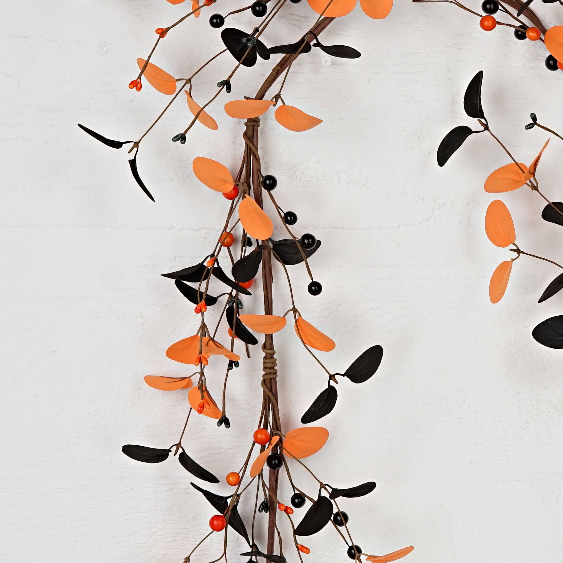Decorative branch with orange leaves and black berries on a white background
