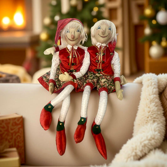 Two Christmas-themed Joe Spencer dolls sitting on a couch with a festive background