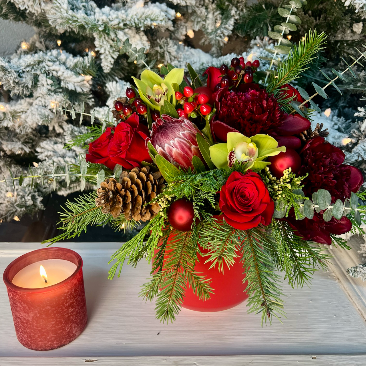 large red flower arrangement with candle and tree background