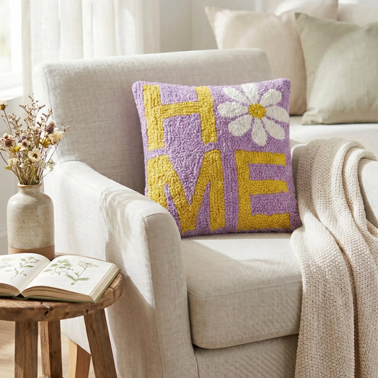 Decorative pillow with 'HOME' and flower design on a couch in a cozy living room.