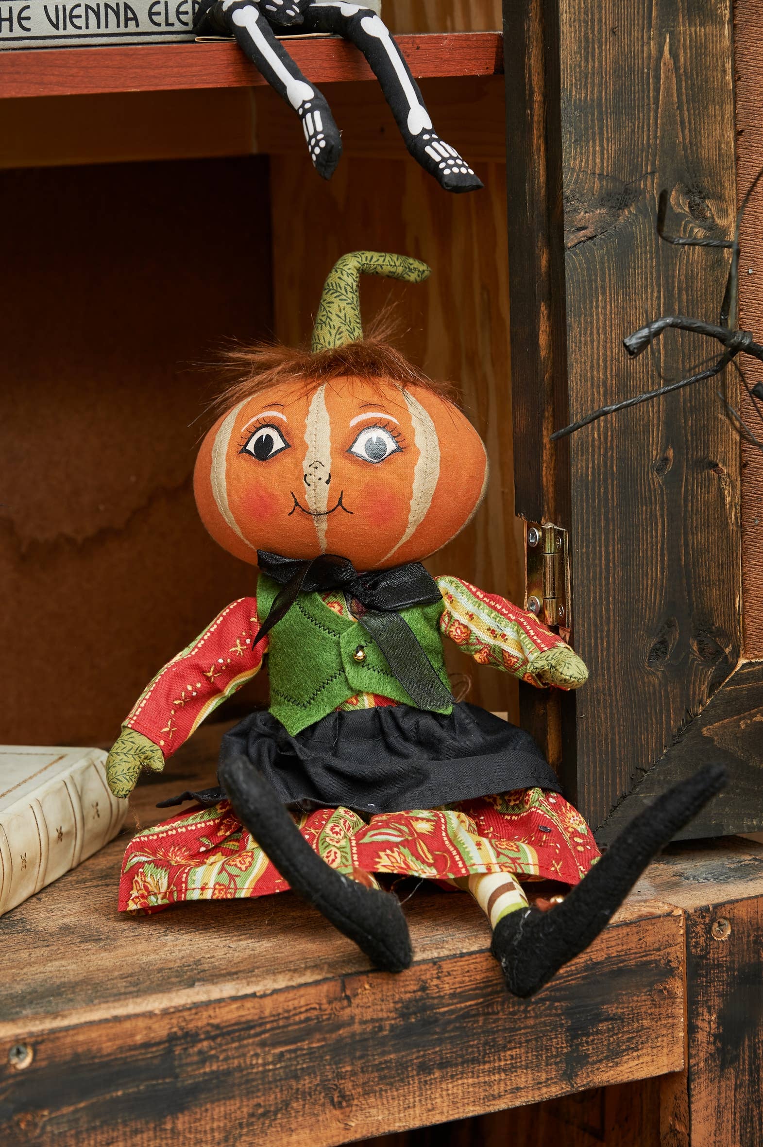 Pumpkin-shaped Joe Spencer doll with a colorful outfit on a wooden surface