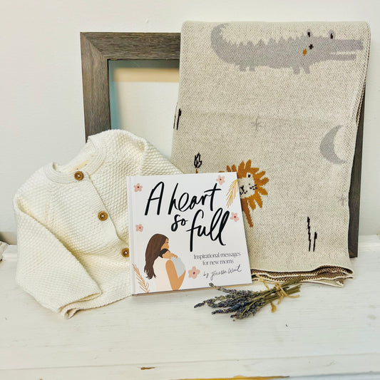 a beautiful gift set for a new baby includes a knit blanket, knit sweater, and book by janessa wait
