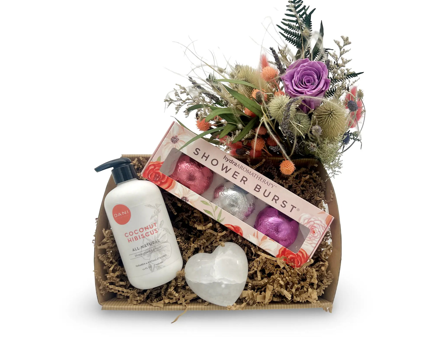 A gift set containing three shower steamers with different scents, a bottle of lotion, and an alabaster stone heart, all arranged in a box with dried floral decoration.