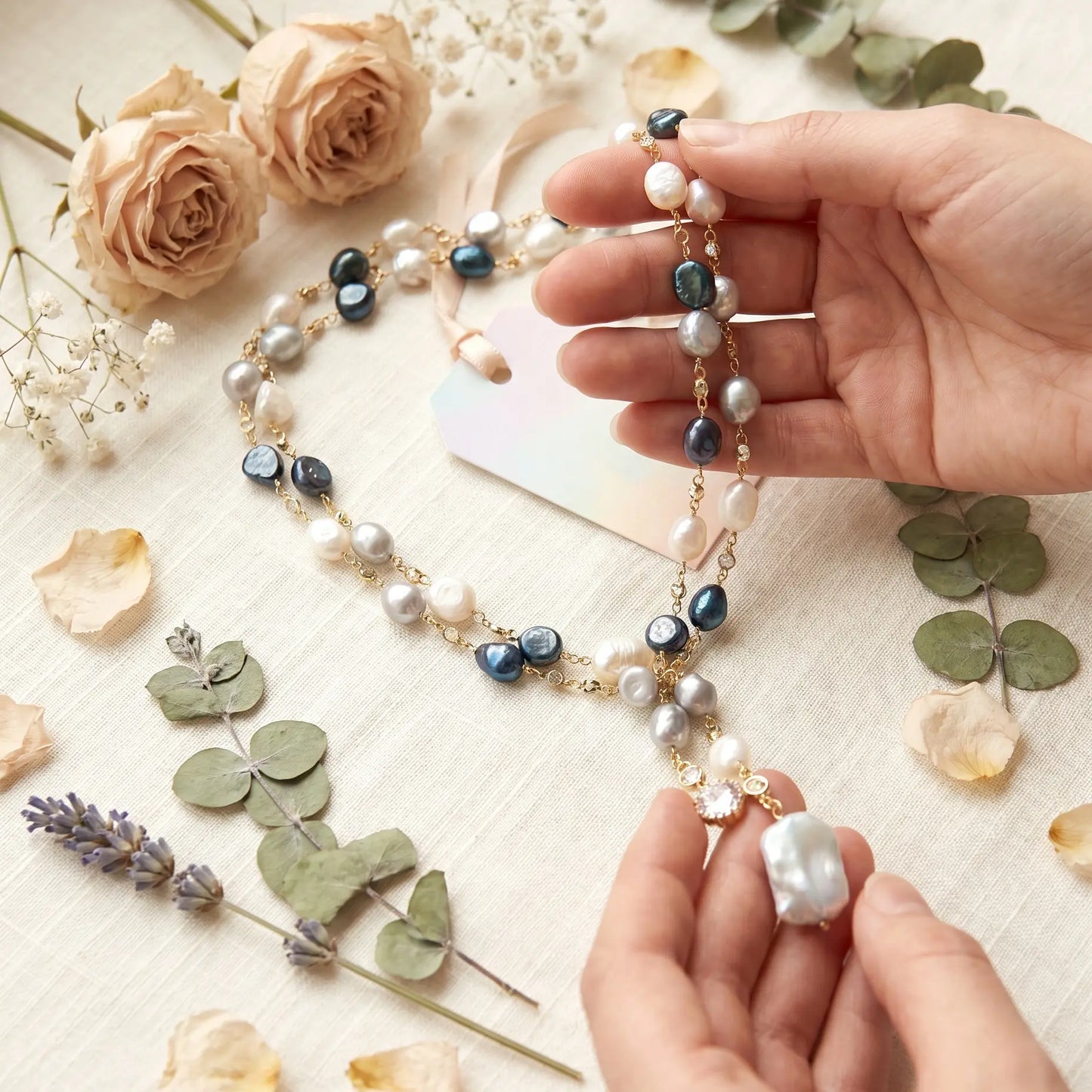 Pearl necklace with blue accents held by a hand on a floral background