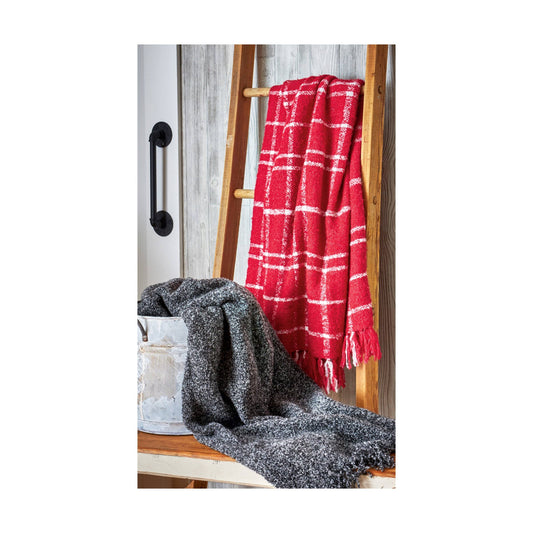 Red plaid blanket draped over a wooden ladder with a gray textured blanket underneath.
