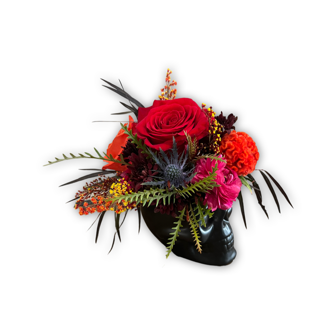 Colorful flower arrangement with red roses, pink carnations, and greenery in a black vase on a white background