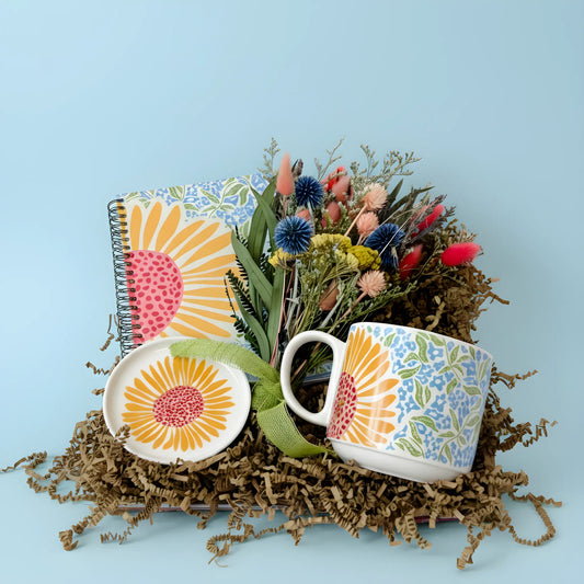 Floral-themed mug, notebook, and plate on a blue background
