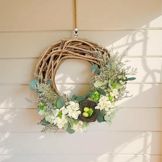spring wreath with nest hanging on outdoor white shiplap wall